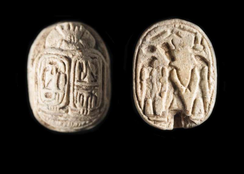 Royal-name scarab of Ramesses II depicting the king at the center with a falcon-headed deity on either side