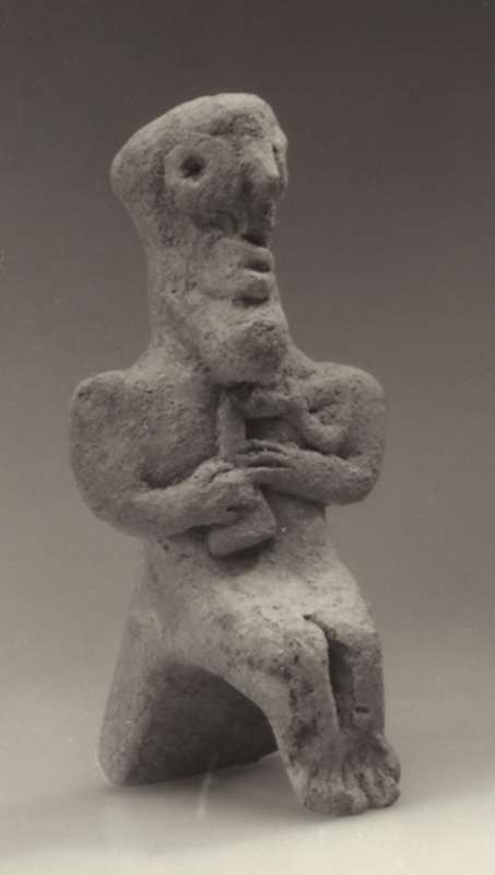 Syrian figurine of a bearded man, seated and holding a curved sickle sword