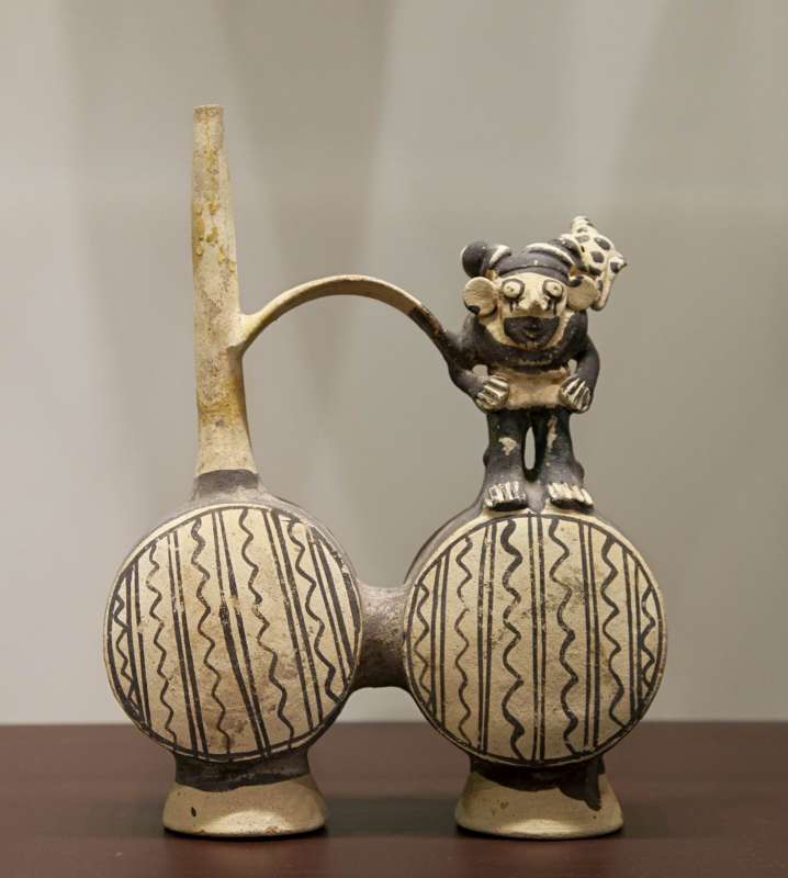 Double-chambered whistling bottle in the form of a human figure carrying a conch shell