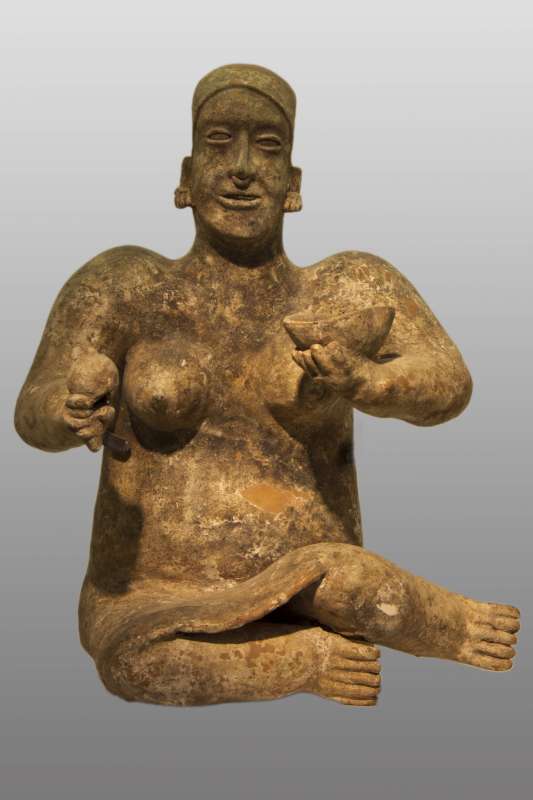 Seated woman holding a rattle and a bowl