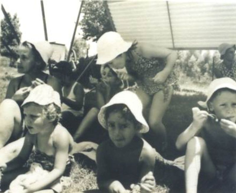 Woman and Children in Bathing Suits Seated on the Grass Eating Grapes